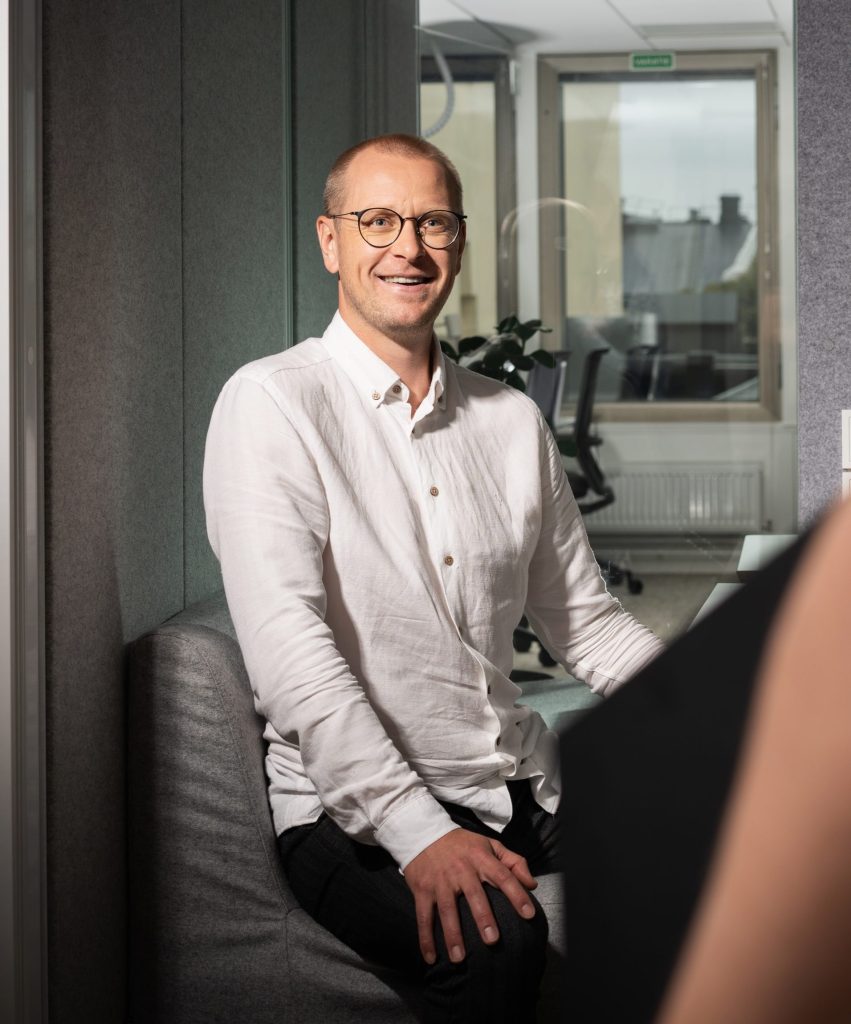 Business-tyylisesti pukeutunut mies keskustelee kollegansa kanssa toimistolla.